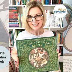 Kobieta z uśmiechem prezentuje piękne książki o wróżkach, w tym "Historia naturalna wróżek" z ilustracją bajkowej postaci.