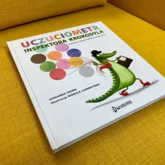 Okładka książki "Uczuciometr Inspektora Krokodyla" z zabawnym, zielonym krokodylem w kapeluszu i z walizką.