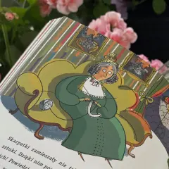 Ilustracja z książki "Sekretna historia skarpetek". Starsza pani w zielonej sukni siedzi na fotelu i dzierga.