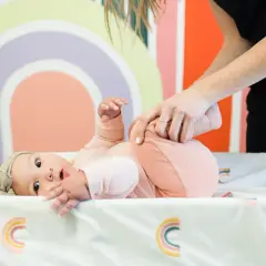Niemowlę ćwiczy, by zmniejszyć wzmożone napięcie obręczy barkowej. Mama delikatnie pomaga w ćwiczeniach.