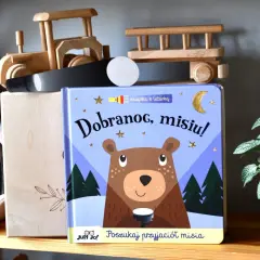 Książka "Dobranoc, misiu!" z latarką, obok pluszowego misia i drewnianych zabawek.
