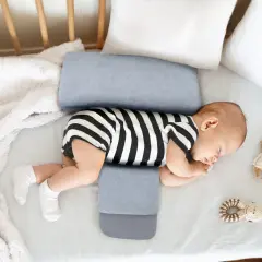 Noworodek śpi na boku, podtrzymywany przez poduszkę klin. Czy poduszka klin jest bezpieczna dla noworodka? Tak, jeśli jest używana zgodnie z zaleceniami.