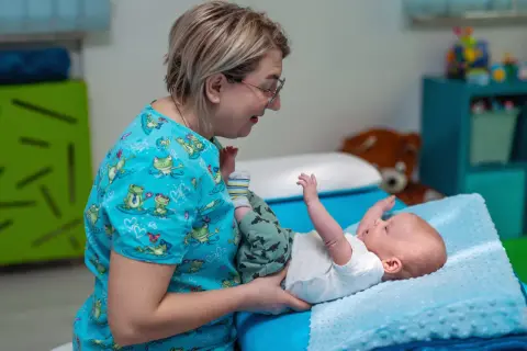 Terapeuta pomaga dziecku z problemem refluksu ukrytego, wykonując delikatne ćwiczenia.